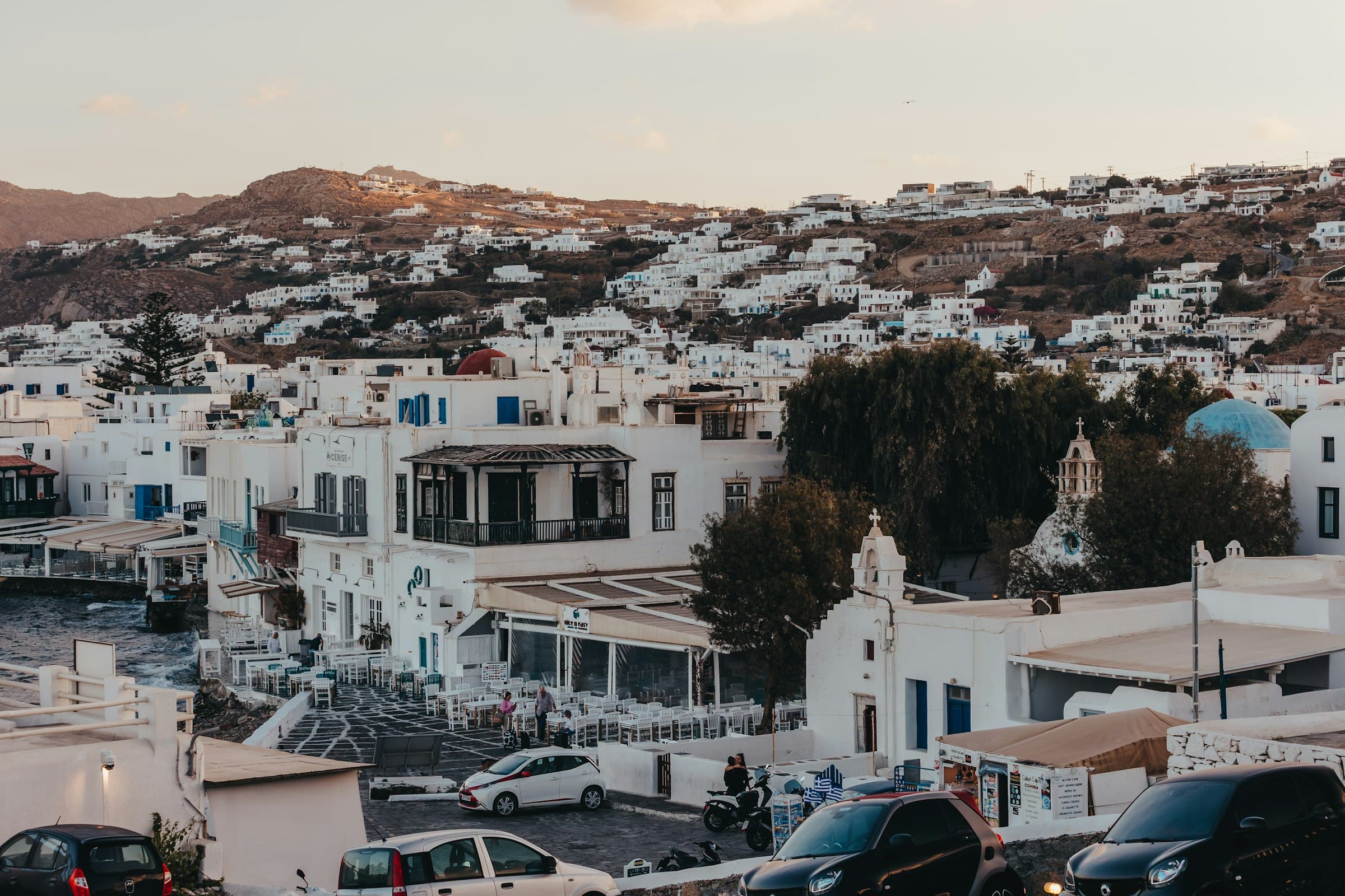 Whitewashed Cycladic buildings cascading down a hillside above the Aegean Sea