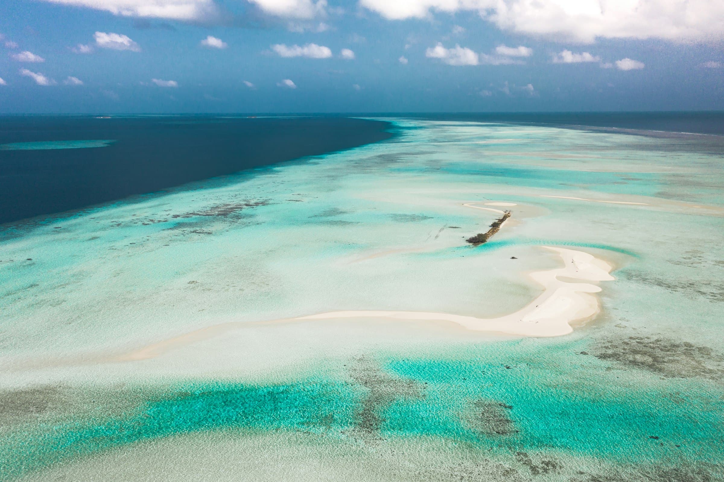 Aerial view of a white sandbar surrounded by turquoise tropical water in the Maldives