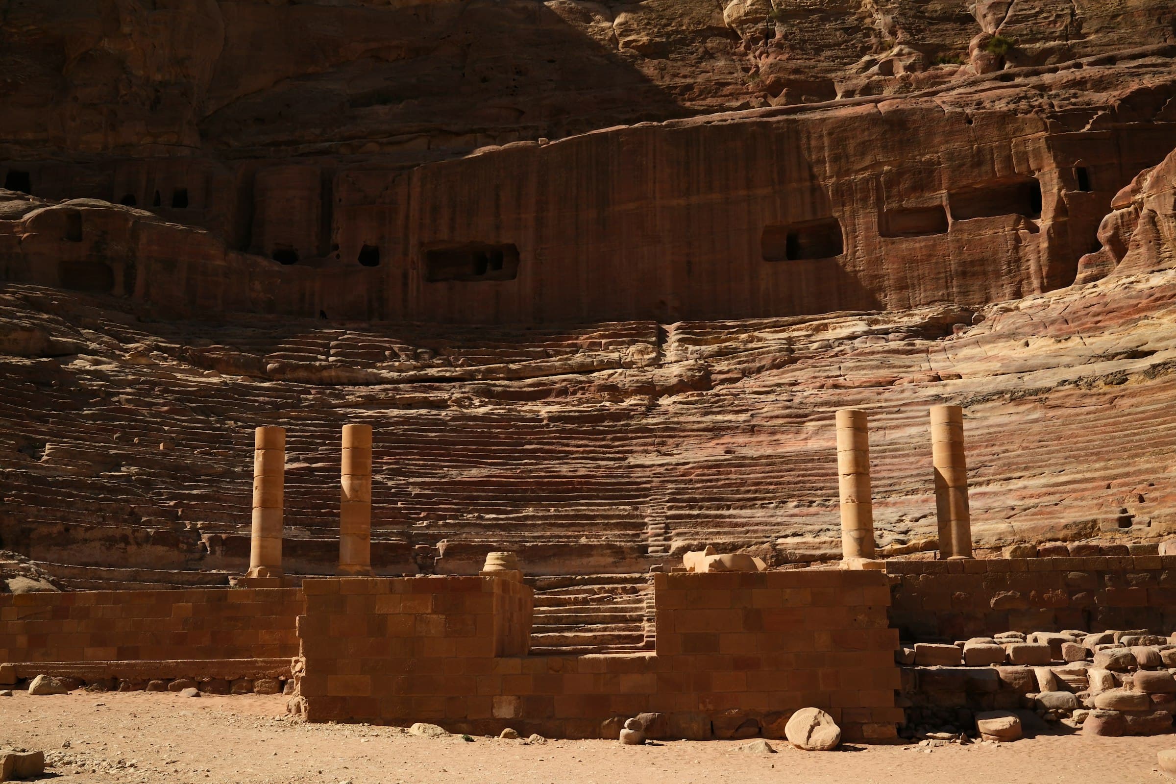 Ancient rock-cut ruins of the Great Theatre carved into the rose-red sandstone cliffs of Petra
