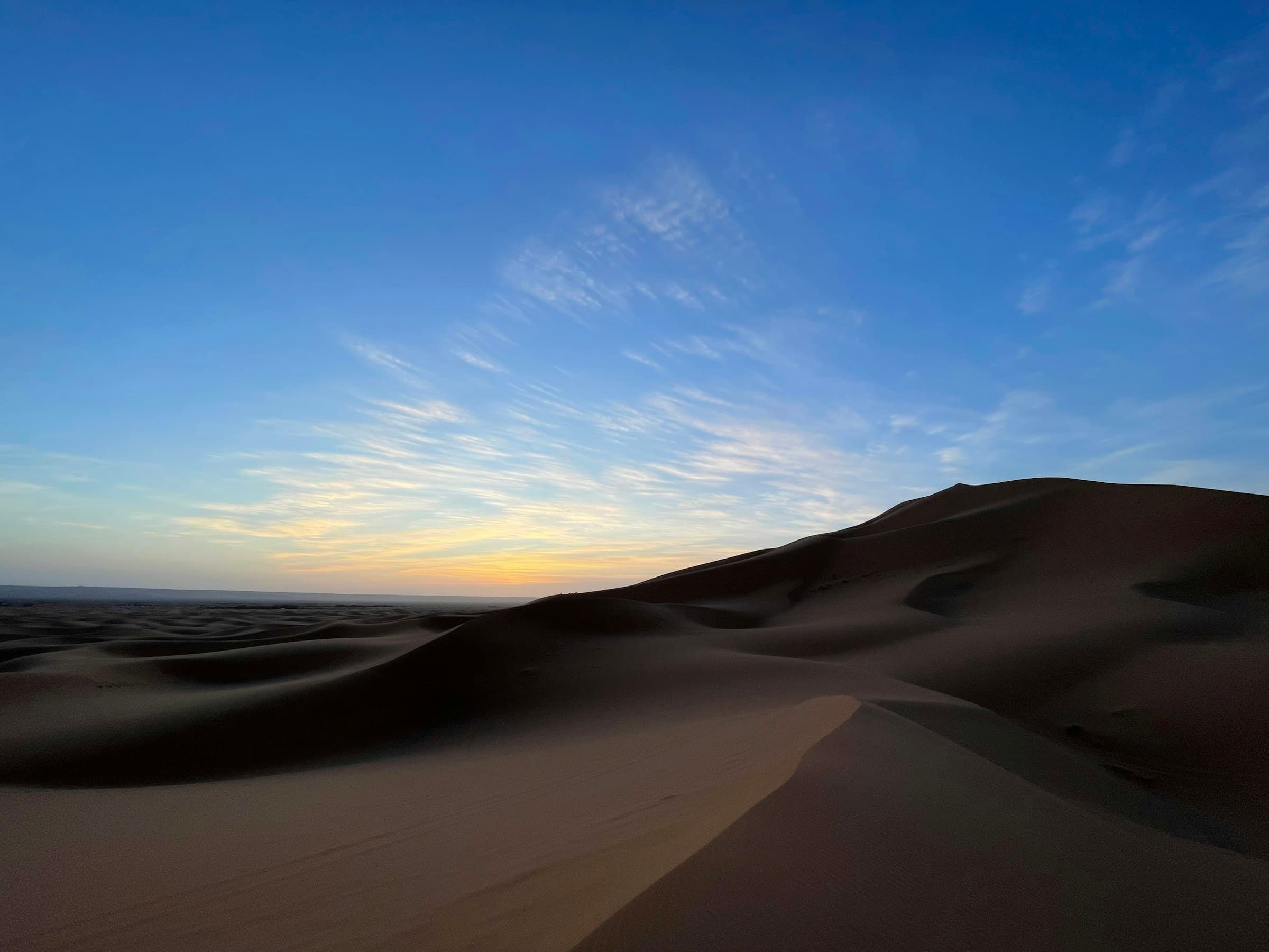 Rippled sand dunes of the Sahara Desert glowing at sunrise, Morocco