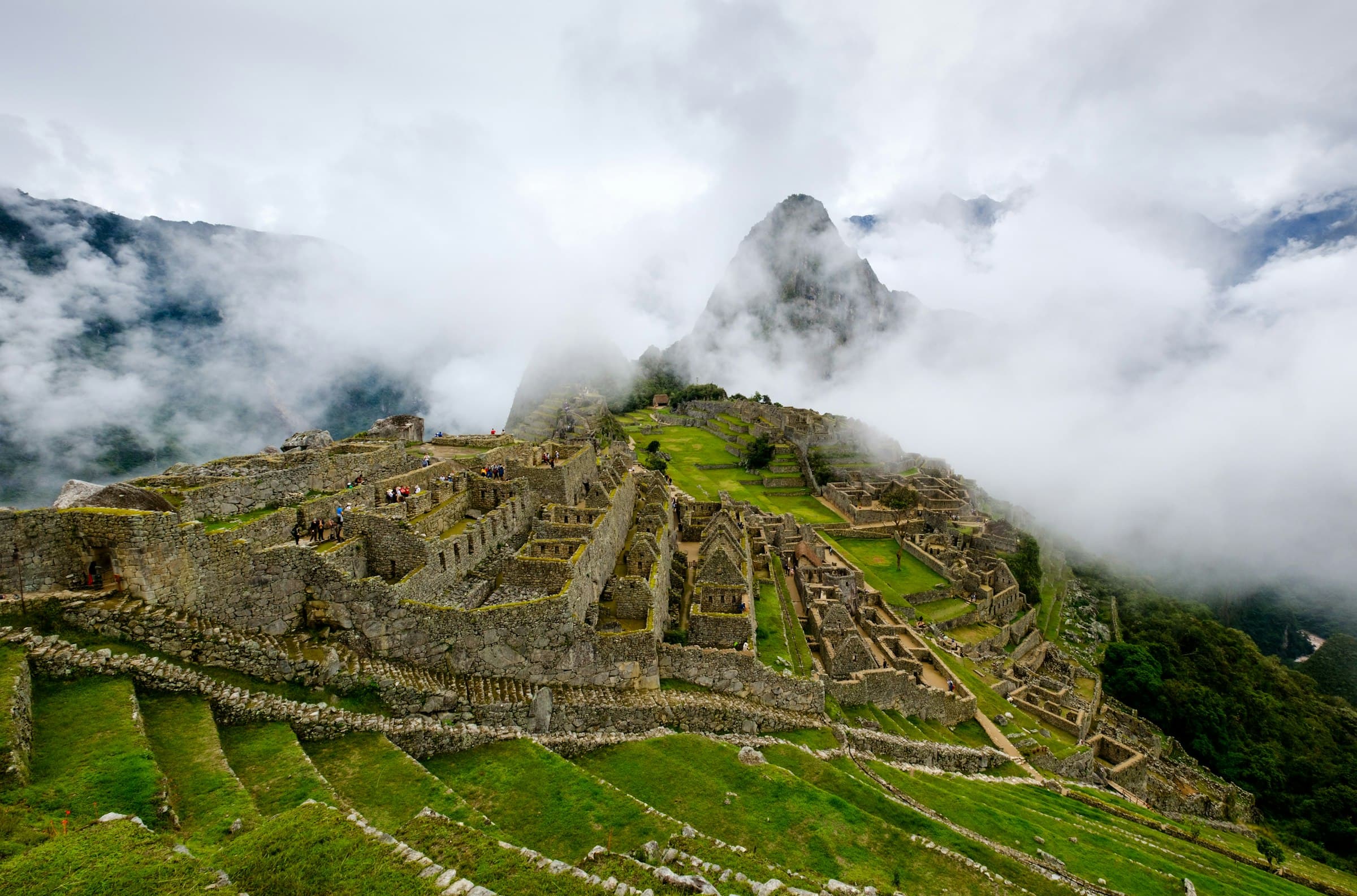 Ancient Incan ruins emerging from mist on a mountainside in Peru