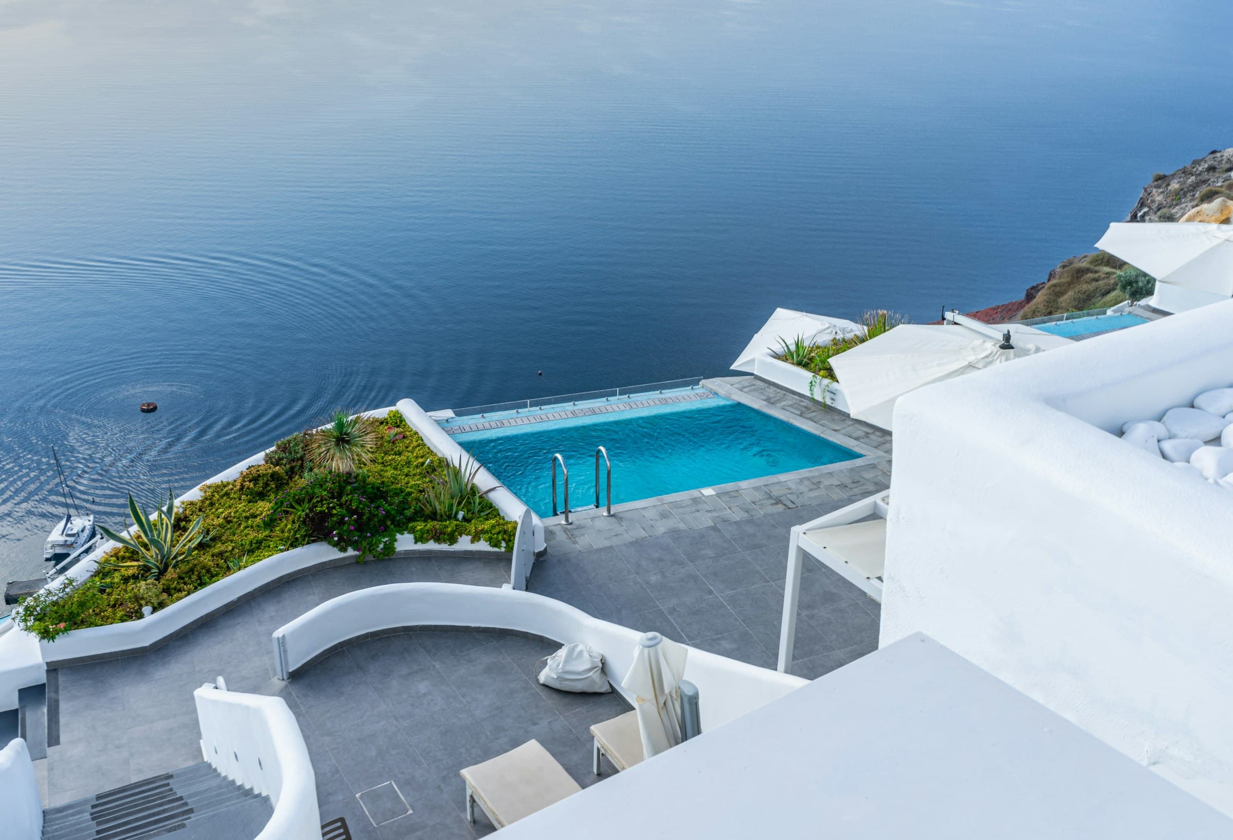 A white cliffside plunge pool overlooking the caldera, in the style of a Santorini cave hotel