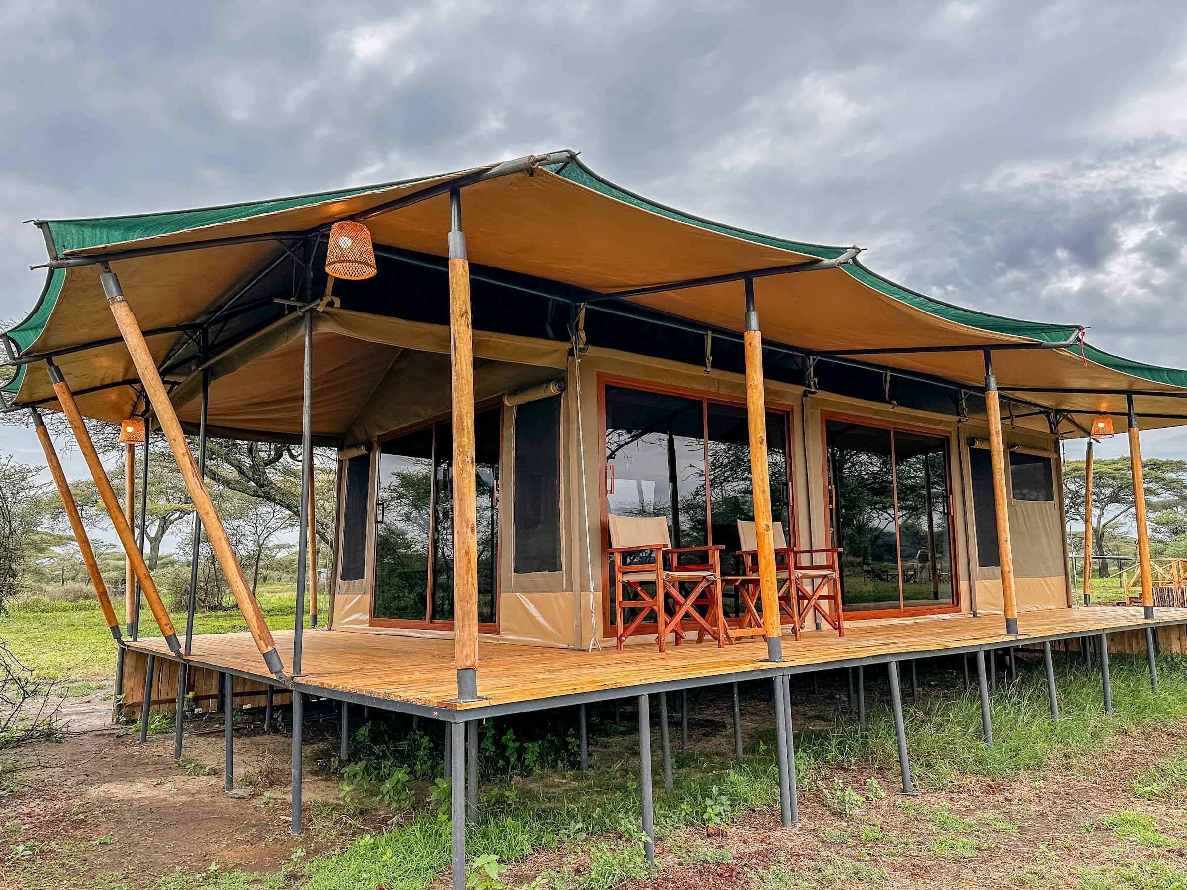 A canvas safari tent with a covered porch set in the bush