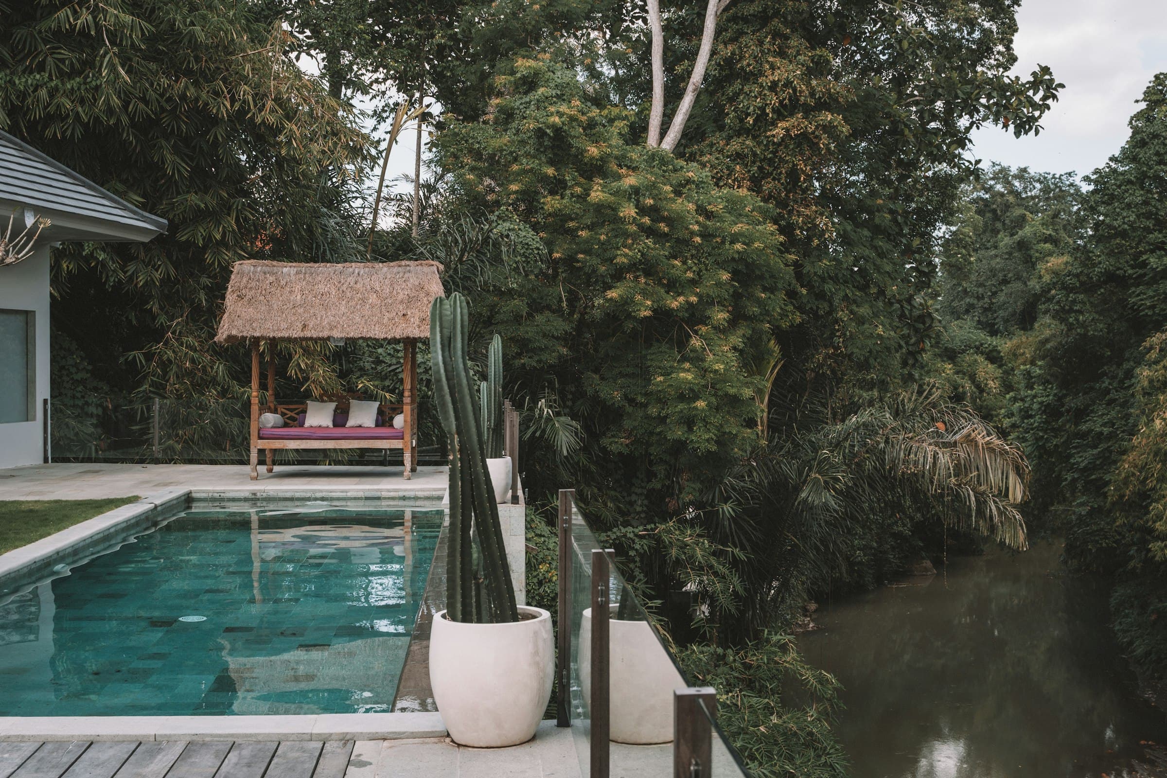 A private swimming pool surrounded by lush green trees at a tropical Bali villa