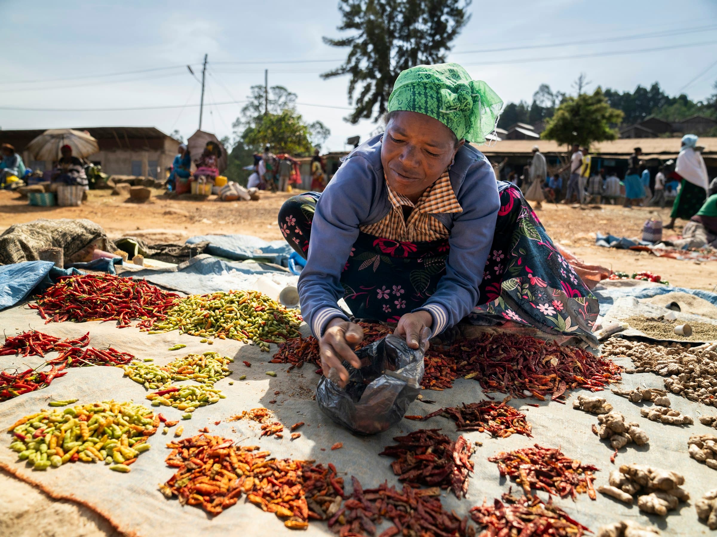 A woman selling spices and produce at a lively outdoor market