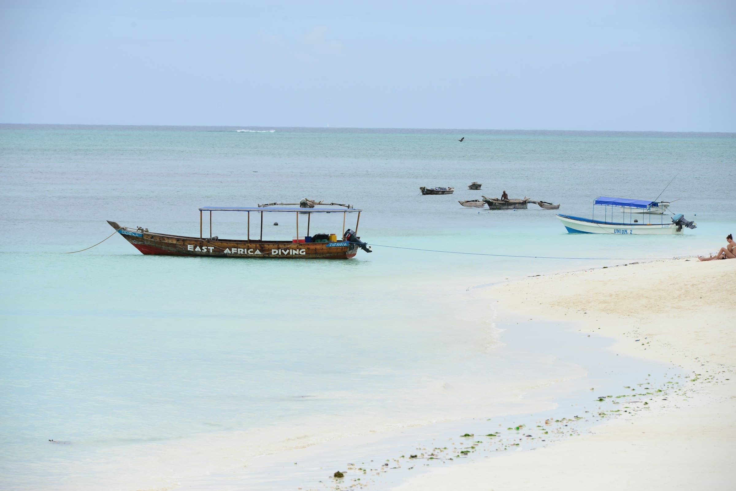 Traditional wooden dhow boat resting on a white sand beach in Zanzibar