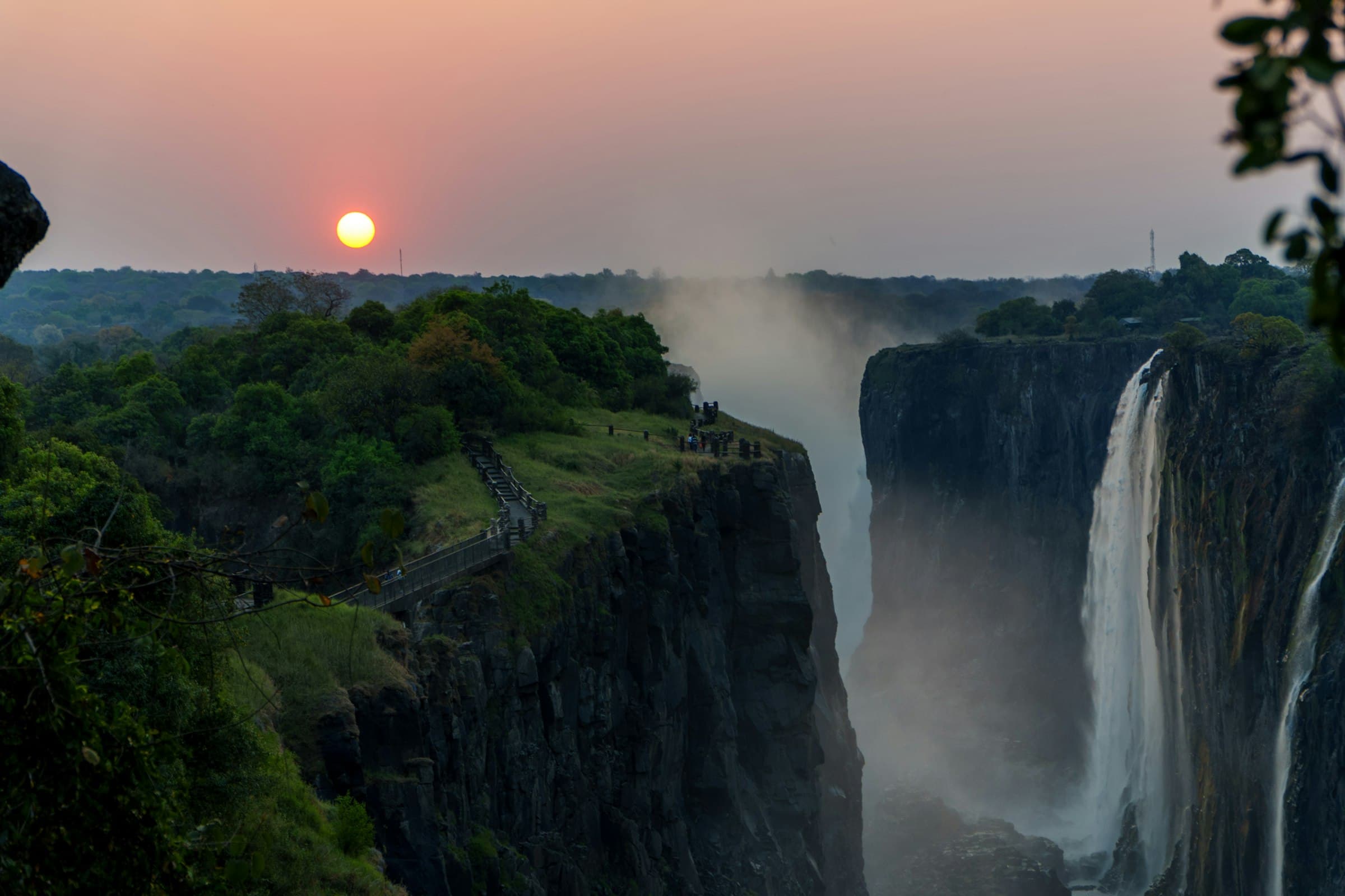 Sunset over Victoria Falls with mist rising from the cascading water
