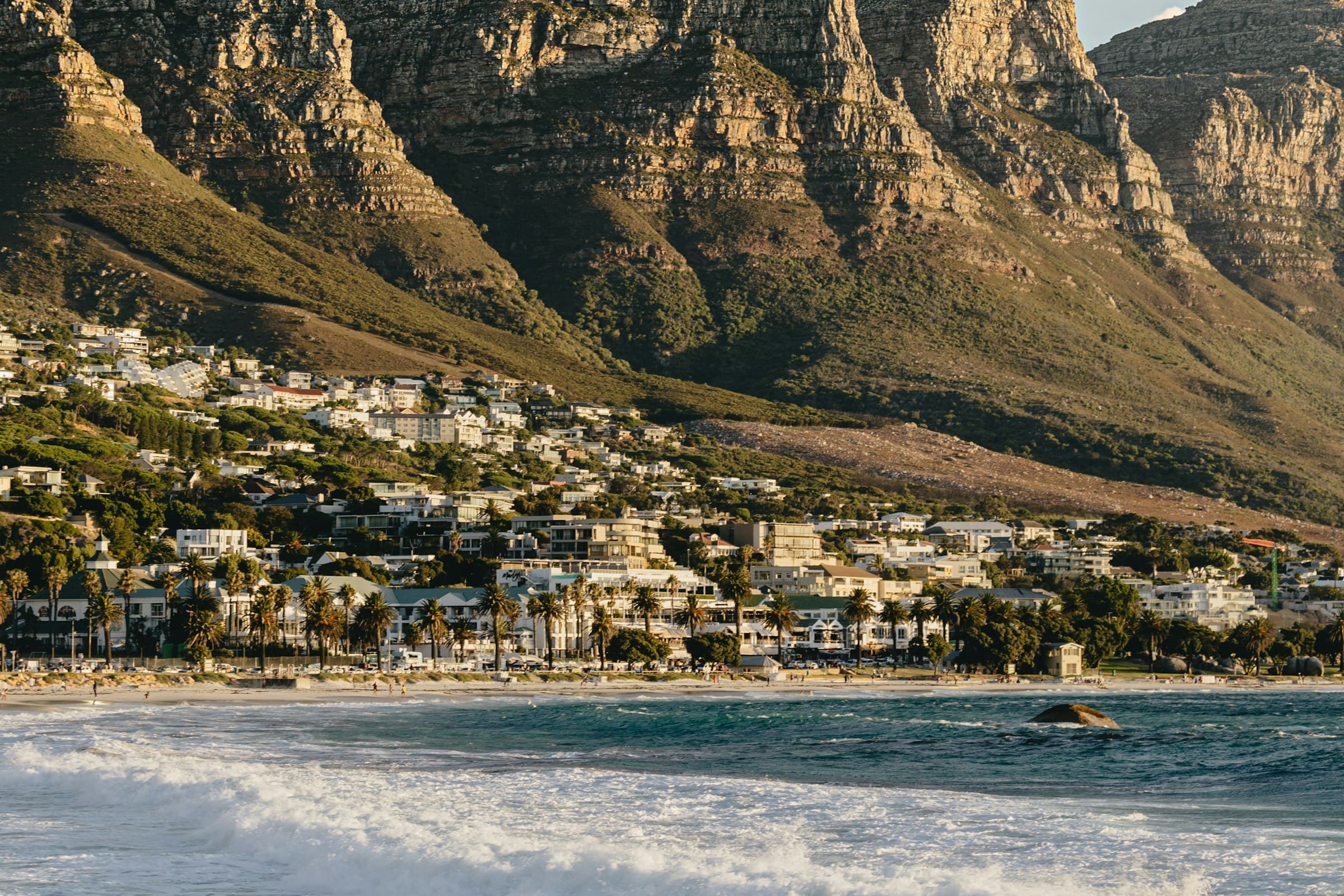 Camps Bay beach in Cape Town with the Twelve Apostles mountains glowing in late-afternoon light
