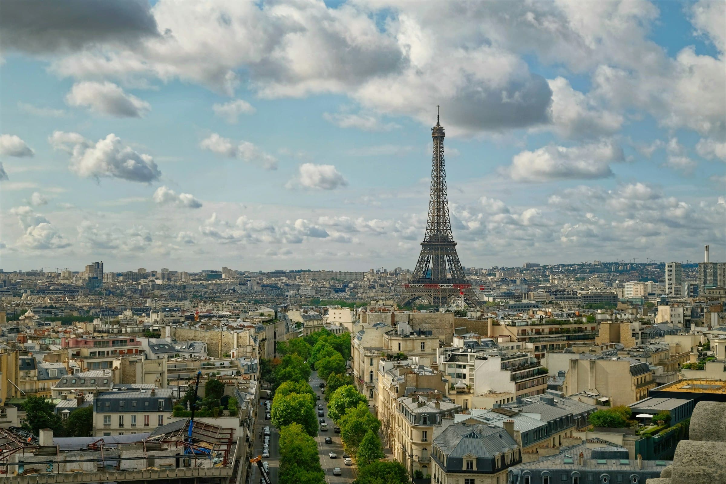 The Eiffel Tower rising above the Paris rooftops under a dramatic cloud-filled sky