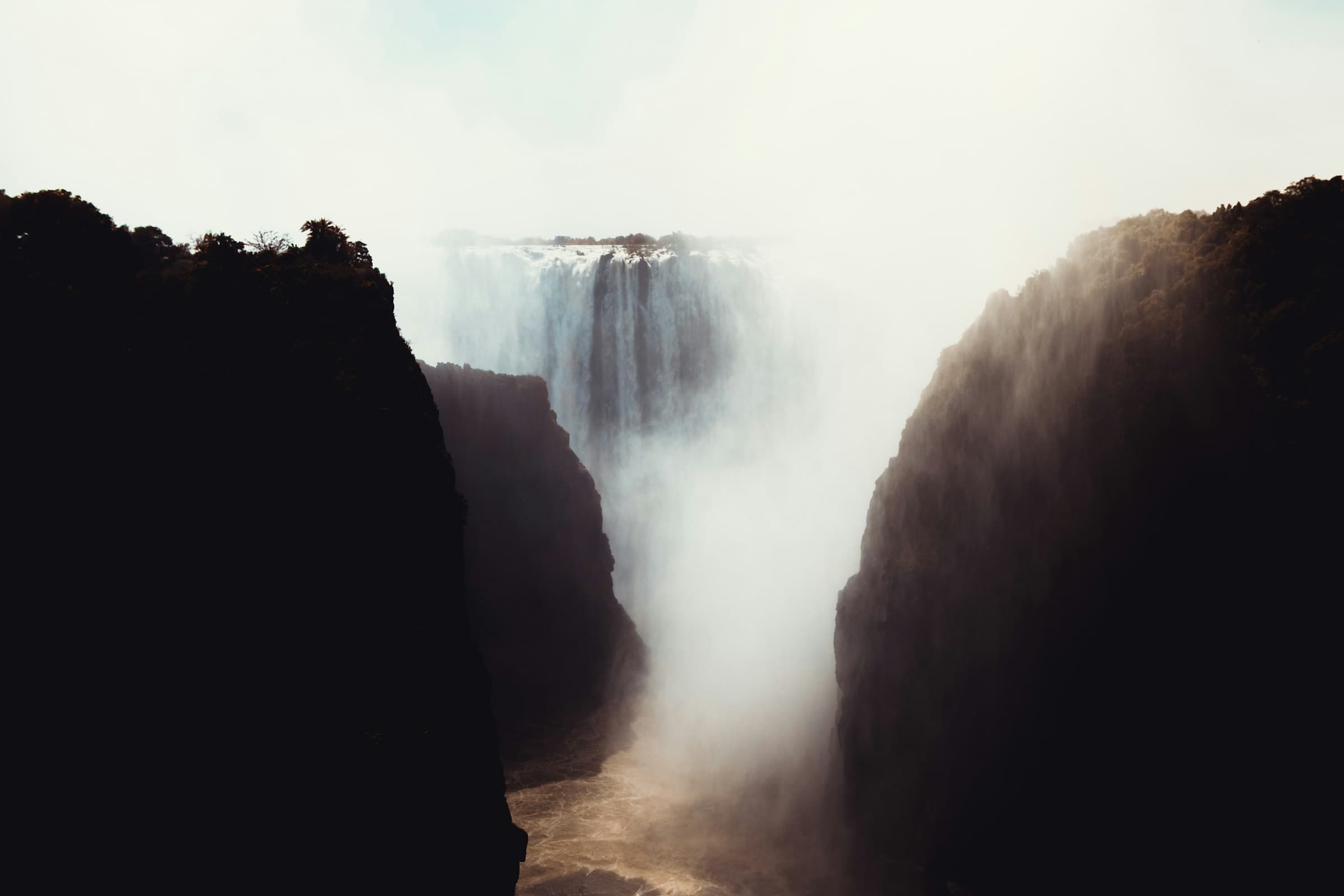 Victoria Falls plunging into the Zambezi gorge, with spray rising between dark basalt cliffs